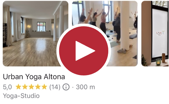 Screenshot aus dem verlinkten Video eines Yogastudios. Im Video ist zu sehen, wie eine Gruppe Frauen Yoga macht, die Kamera fährt dabei langsam von links nach rechts durch den Raum.