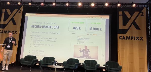 Manuel Gerlach auf der Campixx Bühne: Der Slide im Hintergrund zeigt bei Manuels Vergleich für OMR-Reviews und das Keyword "software vermarkten"
823 € CPC zu 15.000 € echter Wert