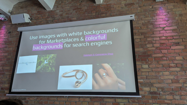 Gemauerte Wand, mit einer Leinwand und Präsentation. Die Präsentation zeigt ein Zitat: "Use images with white backgrounds for Marketplaces & colorful backgrounds for search engines"